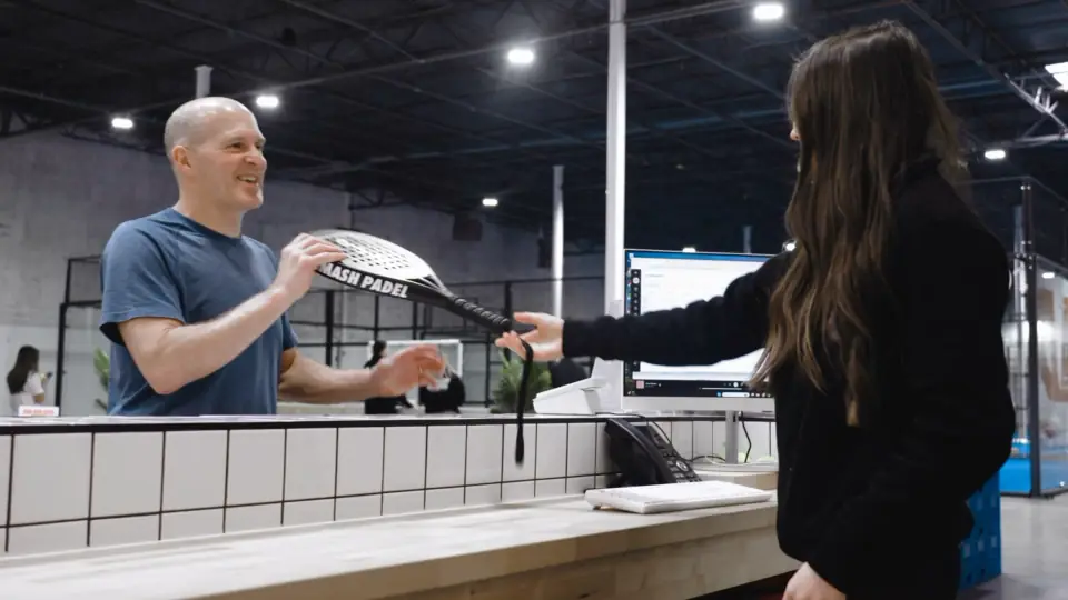 A first-time player receiving a racket at Smash Padel